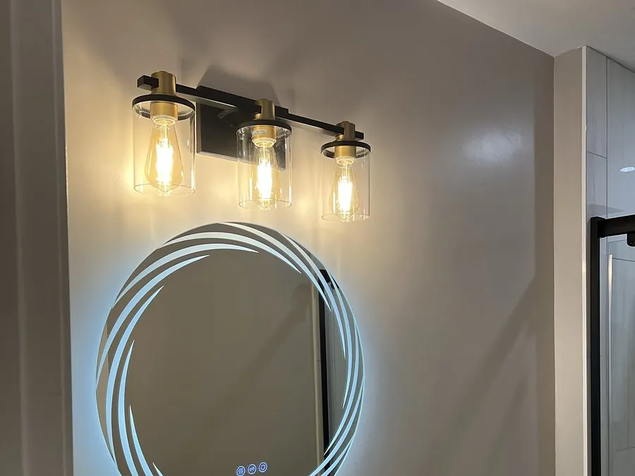 Bathroom vanity light fixture installed above a backlit LED mirror